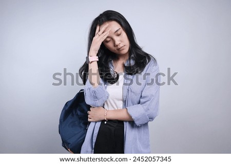 Stressed Young Asian Student Female Suffering From Headache Isolated on Gray Background.  Royalty-Free Stock Photo #2452057345
