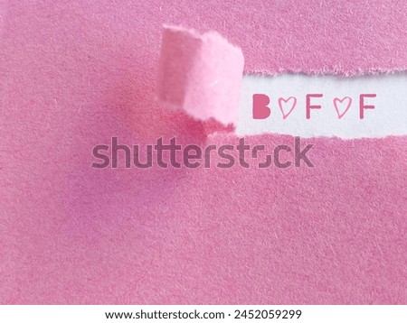 Friendship concept. BFF text behind torn paper background. Stock photo.