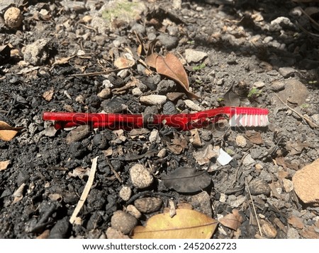 red toothbrush non-degradable material on fertile soil Royalty-Free Stock Photo #2452062723