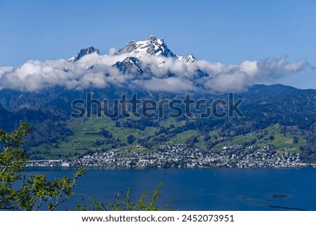 Scenic view of famous snow covered Pilauts mountain with Swiss village of Hergiswil with Lake Lucerne on a sunny spring day. Photo taken April 11th, 2024, Kehrsiten, Canton Nidwalden, Switzerland.