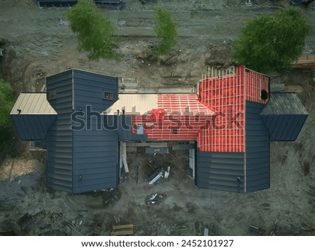 An aerial view of a multi-family building's new roof, with some sections still lacking sheet metal covering, showing ongoing roofing insulation and construction work. Royalty-Free Stock Photo #2452101927