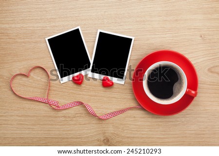 Blank photo frames and red coffee cup on wooden background