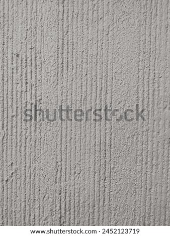 The rough surface adds depth and character to the wall, creating a sense of strength and stability. Light casts subtle shadows along the ridges, accentuating the linear pattern.  Royalty-Free Stock Photo #2452123719