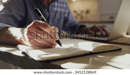Hand, notebook and writing with person in home for finance management, planning or wealth closeup. Agenda, book and schedule with notes in apartment for appointment, information or research on laptop Royalty-Free Stock Photo #2452128869