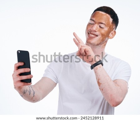 Happy man, vitiligo and selfie with peace sign for memory, picture or photography on a white studio background. Young or handsome male person with smile or emoji for capture, moment or social media
