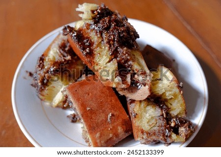 Sweet chocolate and peanut martabak, in a white plate on a wooden table, Indonesian food, stock photo.