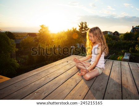 Girl meditating outdoors. Child practicing yoga