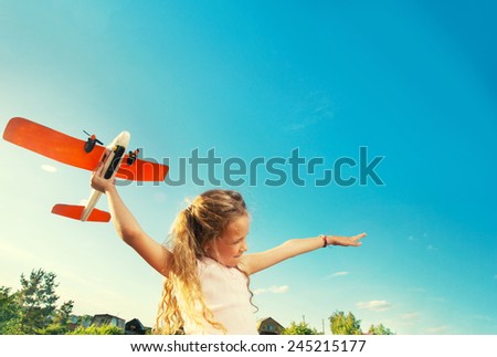 Child playing with plane. Happy girl play outdoors