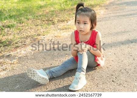 Closeup image of a little girl showing a knee injury after a workout, outdoors suffering from a knee injury while exercising and running. Healthcare and sport concept.