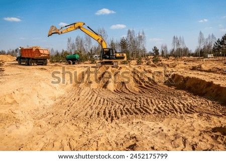 work of an excavator and dump truck at a construction site in sunny weather