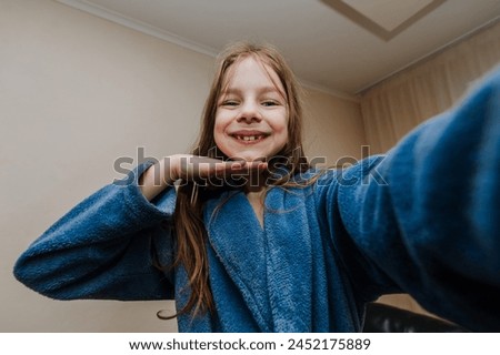 A smiling girl, a cheerful child teenager photographs herself with a camera, smartphone, phone showing a grimace on her face, smiling, grimacing. Photography, portrait.