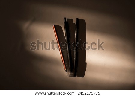 three pens with sunlight and surrounded by shadows Royalty-Free Stock Photo #2452175975