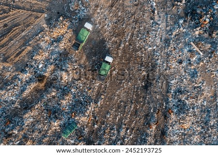 Aerial top down view of garbage trucks unload pile of waste at landfill. Dump of unsorted waste garbage pile in trash dump. Environmental pollution and ecological disaster. View from drone Royalty-Free Stock Photo #2452193725