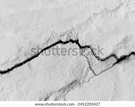 Big long tortuous crack on old plastering wall. Copy space. Black and white photo. Selective focus. Royalty-Free Stock Photo #2452203427