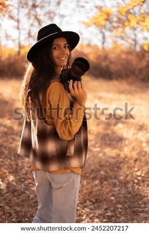 Hispanic female tourist photographer taking pictures of autumn yellow forest park. Copy space