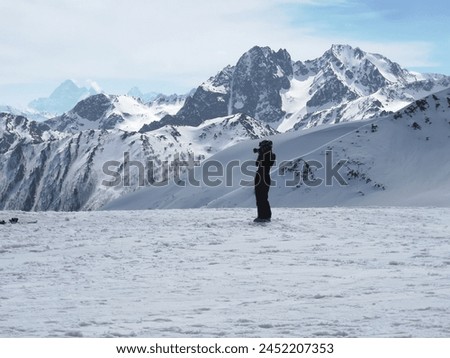A skier takes pictures of the mountains between skiing sessions.