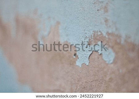 Blue peeling paint on the wall. Old concrete wall with cracked flaking paint. Weathered rough painted surface with patterns of cracks and peeling. High resolution texture for background and design.