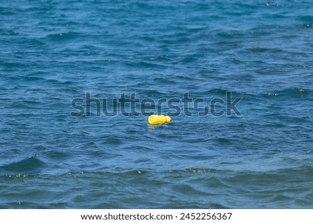 Horizontal picture of isolated yellow bottle floating on calm water