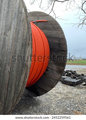 A wooden reels with an orange cable on a construction site. Side view close up
