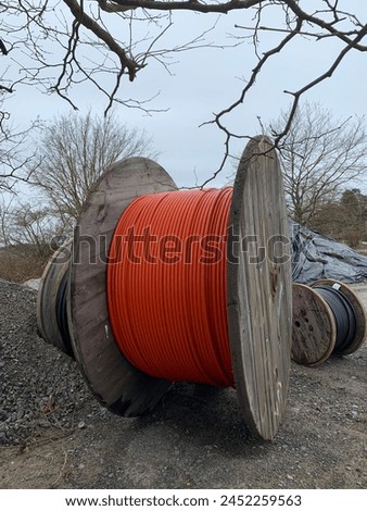 Three different sized wooden reels with a cable on a construction site. Side view. Vertical photo.