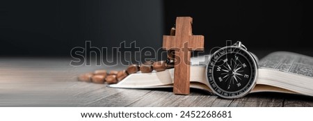 Open Bible on wooden table, compass on it and wooden cross, word of God as guidance concept Royalty-Free Stock Photo #2452268681