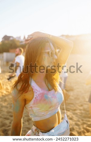 Happy woman covered in rainbow colored powder celebrating holi color festival. Young woman having fun with colorful powder outdoors. Beach party. Traditional Indian holiday.