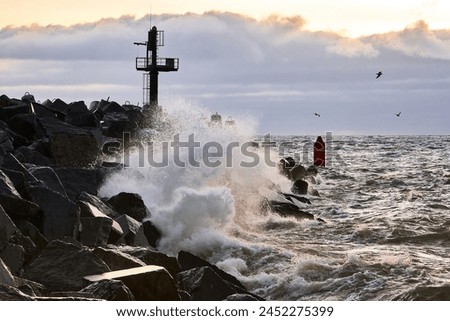 Seascape with a breakwater and a view of the water. Strong waves break against a protective structure made of concrete Royalty-Free Stock Photo #2452275399