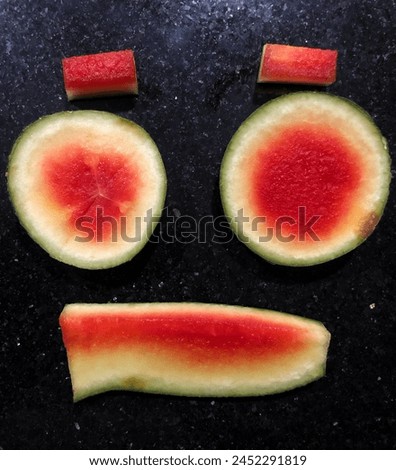 Make a funny monster face like in a cartoon from pieces of red watermelon rind