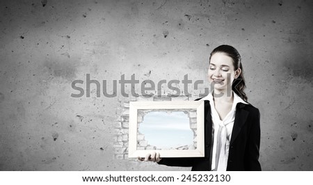 Young woman holding wooden frame with cloud scape