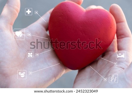 Doctor holds a heart in his hand and shows medical icons on the virtual panel. Healthcare concept.
