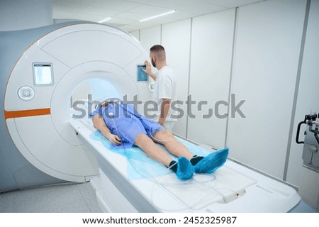 Medical professional positioning man for contrast-enhanced brain MRI Royalty-Free Stock Photo #2452325987