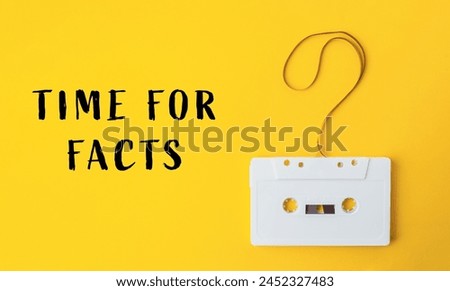 A white cassette tape is hanging from a string with the words Time for Facts written below it
