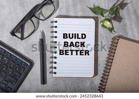 Build back better text on a notepad page on a gray background near banknotes and a magnifying glass