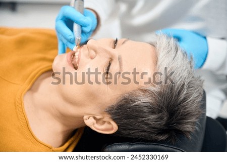 Dentist removing plaque and tartar buildup during professional hygienic cleaning Royalty-Free Stock Photo #2452330169