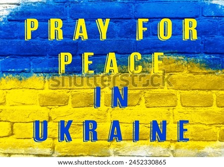 A blue and yellow sign that says pray for peace in Ukraine. The sign is on a brick wall