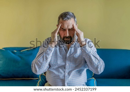 Bearded Businessman Feeling Tired Exhausted, Chronic Work Stress. Man Suffering From Headache After Hard Working Day, Sitting On Couch At Home Royalty-Free Stock Photo #2452337199