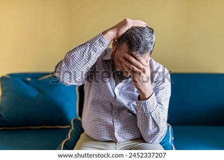 Bearded Businessman Feeling Tired Exhausted, Chronic Work Stress. Man Suffering From Headache After Hard Working Day, Sitting On Couch At Home Royalty-Free Stock Photo #2452337207