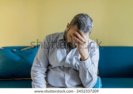 Bearded Businessman Feeling Tired Exhausted, Chronic Work Stress. Man Suffering From Headache After Hard Working Day, Sitting On Couch At Home Royalty-Free Stock Photo #2452337209