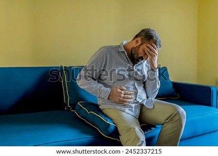 Bearded Businessman Feeling Tired Exhausted, Chronic Work Stress. Man Suffering From Headache After Hard Working Day, Sitting On Couch At Home Royalty-Free Stock Photo #2452337215