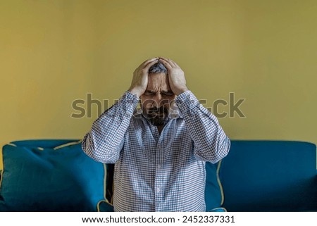 Bearded Businessman Feeling Tired Exhausted, Chronic Work Stress. Man Suffering From Headache After Hard Working Day, Sitting On Couch At Home Royalty-Free Stock Photo #2452337331