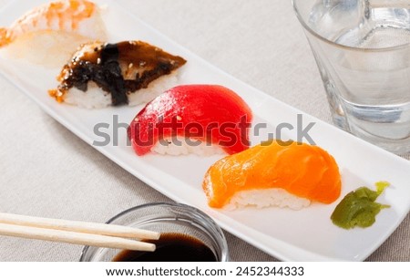 Japanese seafood appetizer. Nigirizushi with fish fillets and prawn served with wasabi and soy sauce on white plate Royalty-Free Stock Photo #2452344333