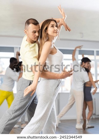 Energy guy and young woman are dancing classic version of waltz in couple during lesson at studio. Leisure activities and physical activity for positive people.