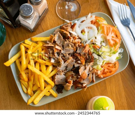 Dish with appetizing assorty of Armenian cuisine of delicious shish kebab, french fries, baked vegetables, fresh tomatoes Royalty-Free Stock Photo #2452344765
