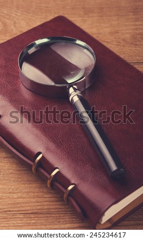 Notebook with a magnifier on wood table