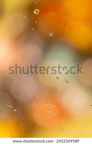 Vertical macro shot of tiny water bubbles on blurred bokeh background, warm orange colours.