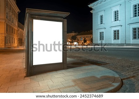 Blank White Mockup Of Vertical Billboard In A Bus Stop At Night. An Empty Advertising Lightbox In The Town Hall Square