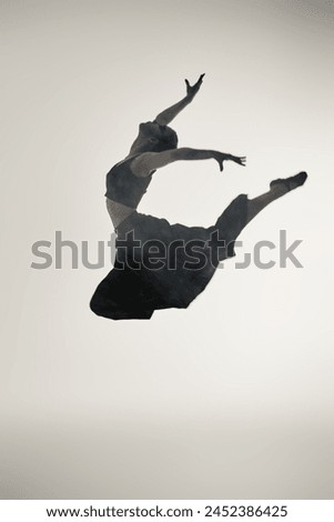 Art portrait of a graceful girl ballerina in a high jump on a white background with haze. Contemporary ballet. Full-length portrait. 