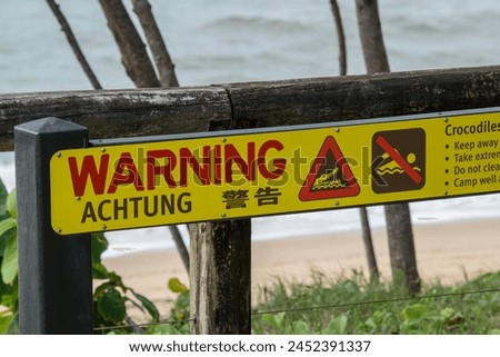 Caution: Crocodile warning sign posted on a beach, indicating danger from recent sightings. Stay safe and aware! North Queensland, Australia