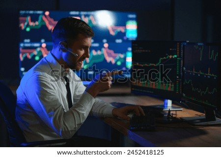 Side view of crypto broker sitting at office table, analyzing market, looking at screen.