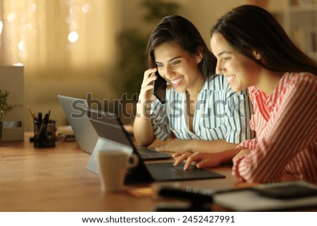 Happy tele workers using multiple devices and talking on phone in the night at home Royalty-Free Stock Photo #2452427991